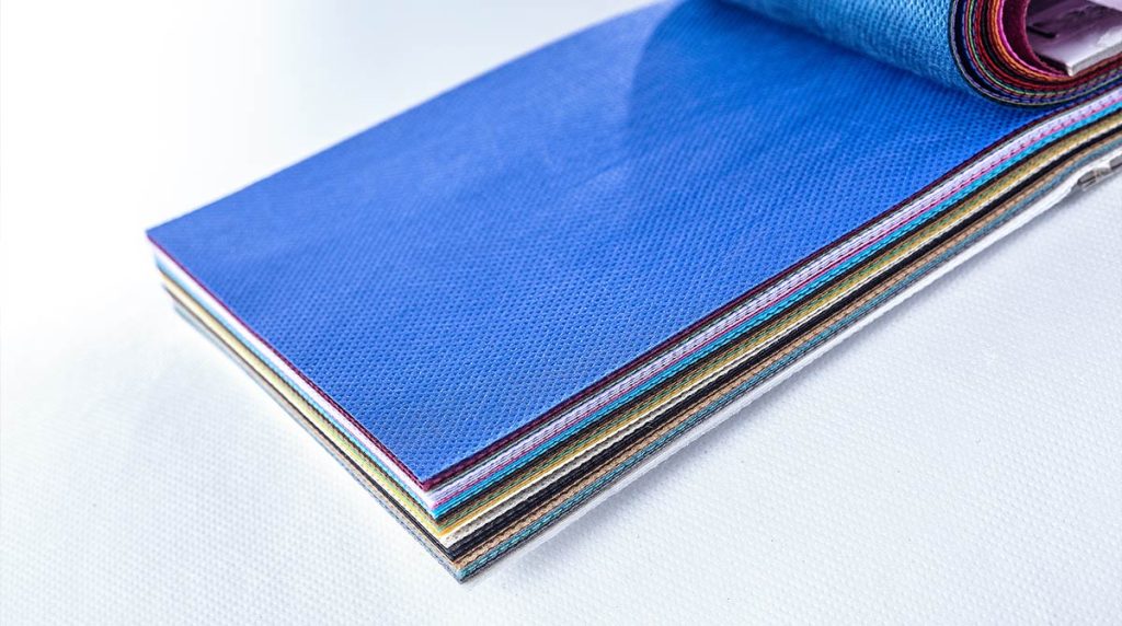 Gestapelte Vlieszuschnitte in verschiedenen Farben, oben ein blaues Vlies