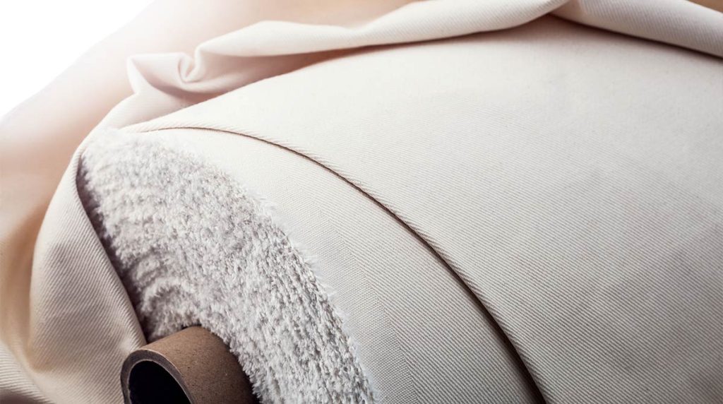 Rolle aus naturweißem Baumwollgewebe auf Papphülse, Nahaufnahme der Stoffstruktur