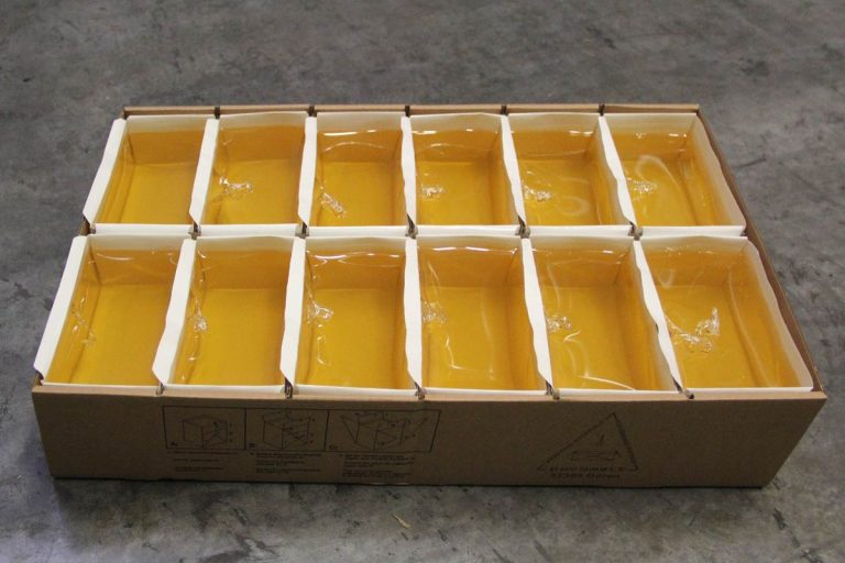 Gelber Industrieklebstoff in offenen Gebinden, verpackt im Versandkarton